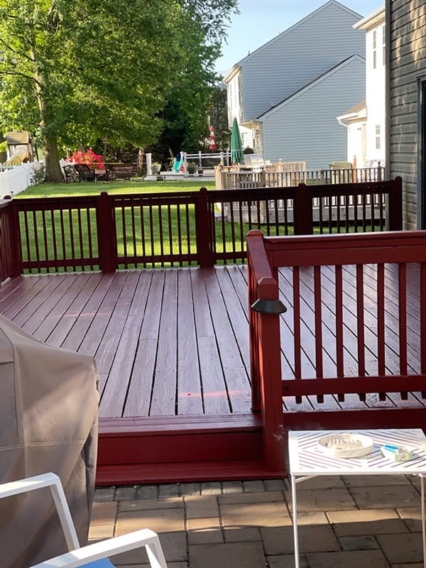 Freshly stained red deck with matching railings in backyard
