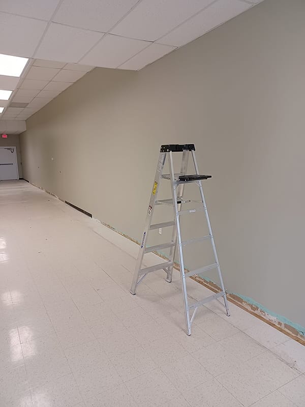 Freshly painted beige wall in commercial hallway with stepladder