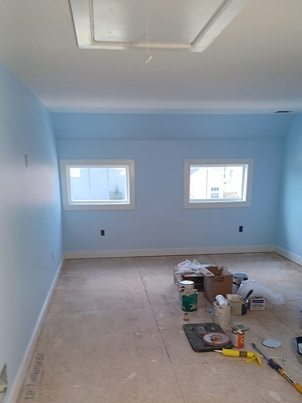 Freshly painted light blue room with paint supplies on floor