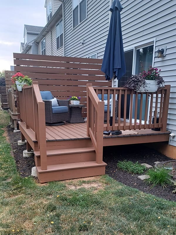 Refinished brown deck with privacy screen and patio furniture