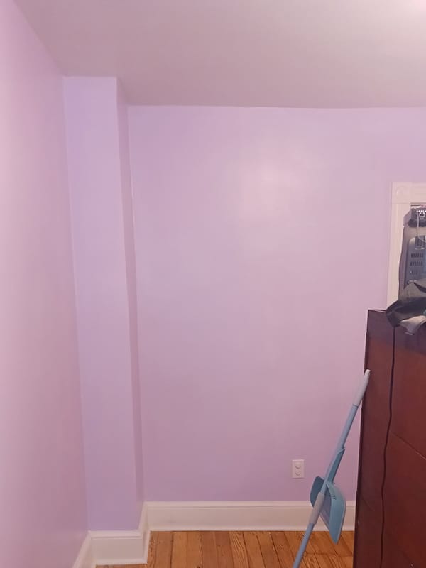 Light purple bedroom interior wall with white baseboard trim