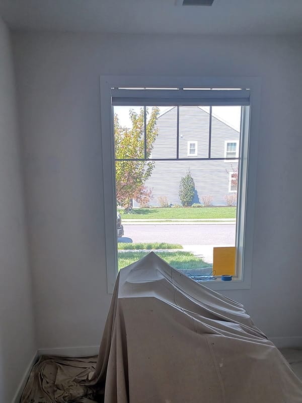 Interior room window framed by drop cloths during wall prep