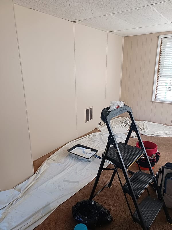 Crisp white painted interior wall with canvas drop cloths on floor