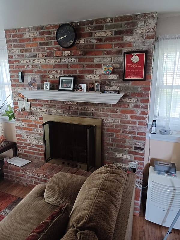 Unfinished red brick fireplace with mantel in traditional living room