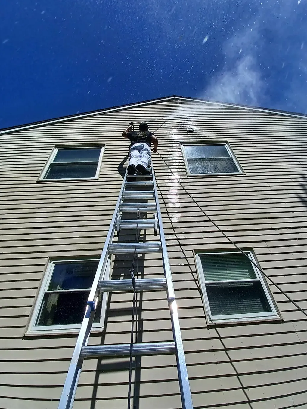 Professional painter pressure washing home exterior siding