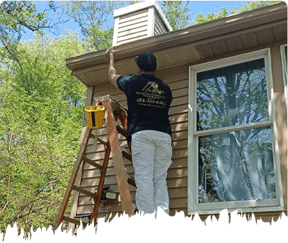 Painter applying exterior trim paint near the roofline